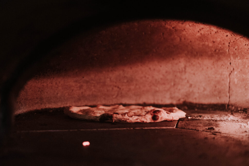 A pizza going into the wood-fired oven